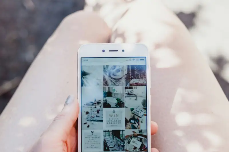 Hand holding a smartphone showing an Instagram feed for social media marketing